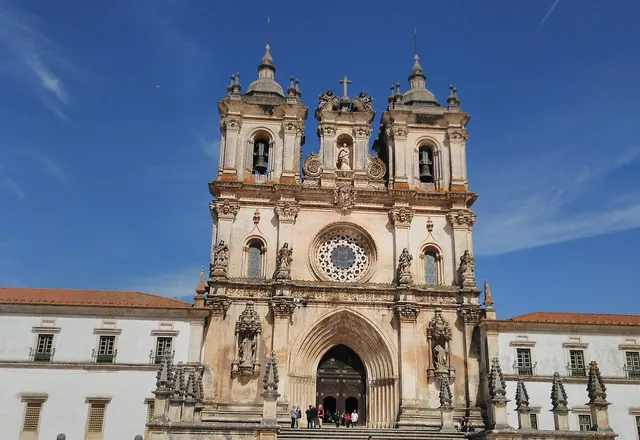 Gothic facade of the Alcobaça Monastery under a blue sky