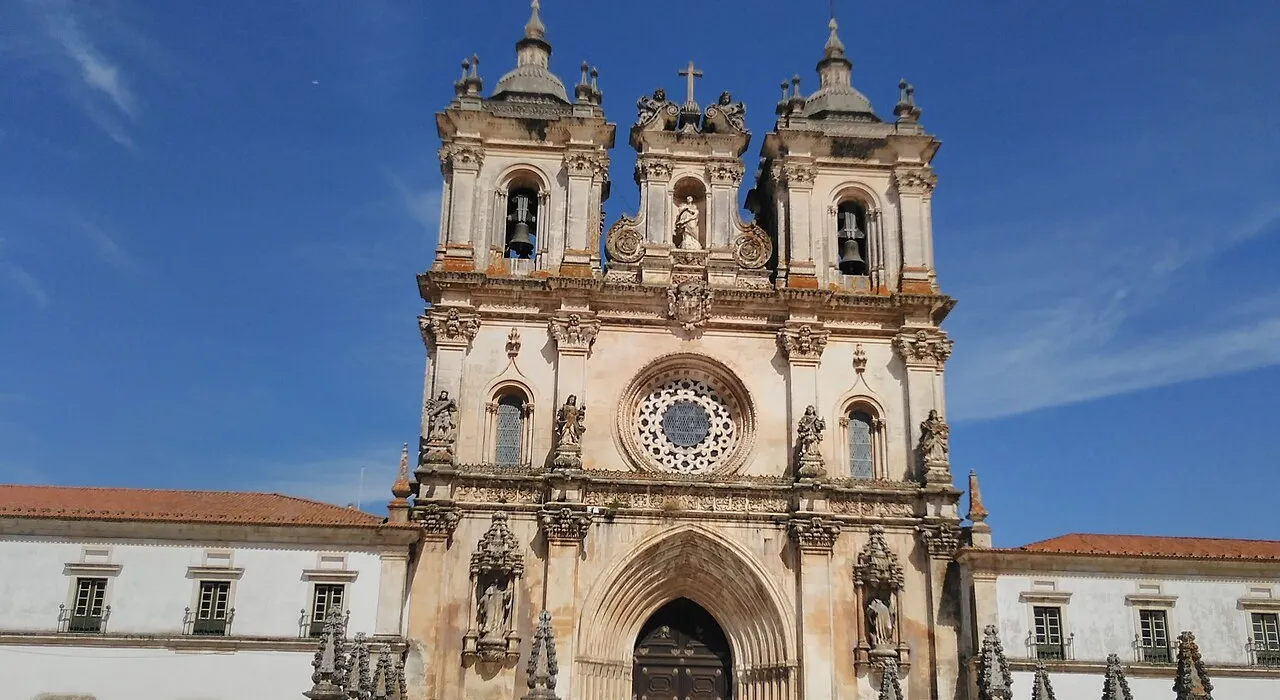 Gothic facade of the Alcobaça Monastery under a blue sky