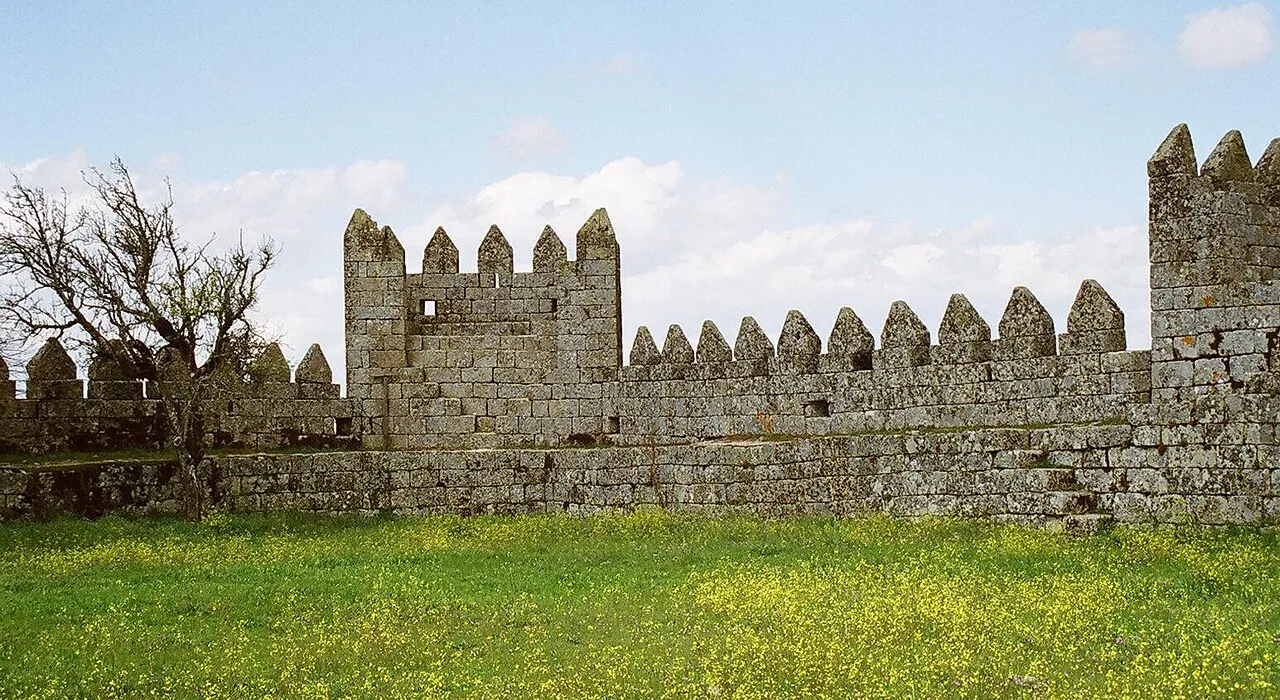 Medieval walls of Trancoso in a field of yellow wildflowers